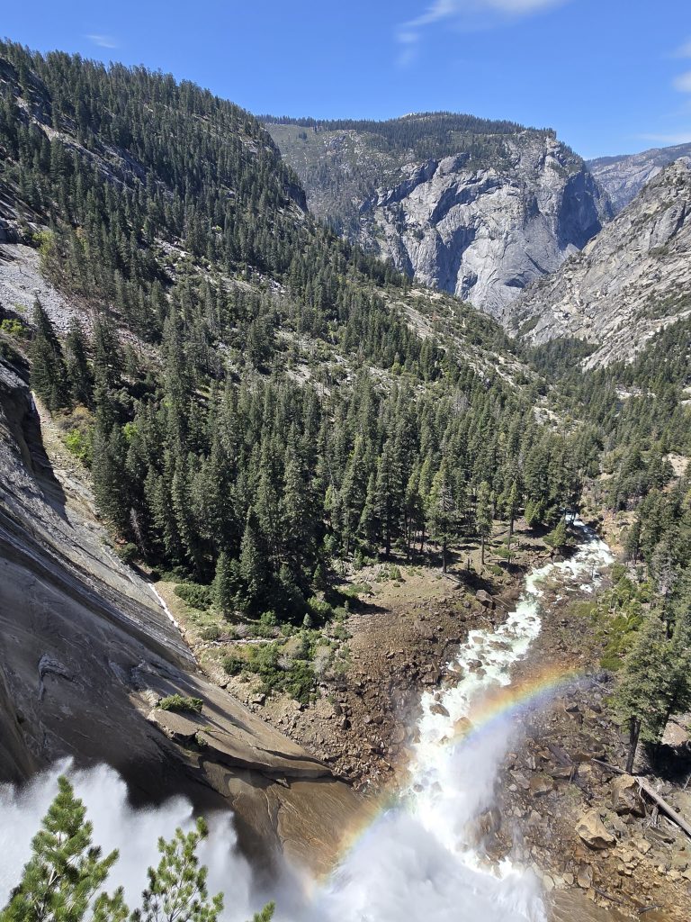In Yosemite, looking down over the top of Nevada Falls with a rainbow in the mist